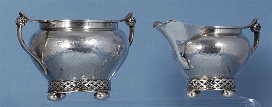 A George V planished silver Arts & Crafts sugar bowl and cream jug, by Albert Edward Jones, jug height 82mm, weight 10.3oz/321grms.